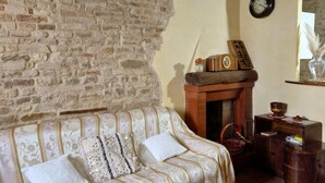 Een gezellige woonkamer met een bakstenen muur, een gestreept sofa, een open haard en een klok aan de muur.