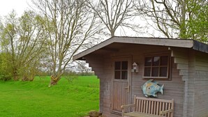 A wooden cabin with a bench outside, a small window, and a decorative fish on the wall. - Ferienwohnung im Ferienhaus Rosi, Fehmarn-schlagsdorf (Fehmarn)