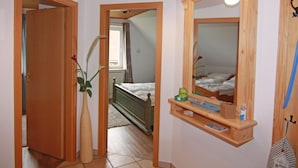 A bedroom with a wooden bed, a bedside table with a mirror, and a small shelf with toiletries. - Ferienwohnung im Ferienhaus Rosi, Fehmarn-schlagsdorf (Fehmarn)
