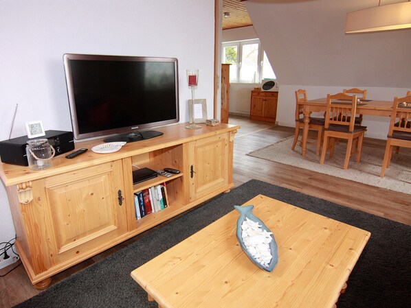 A living room with a television, wooden furniture, a fish-shaped table, and a bookshelf.
