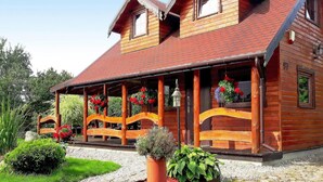 Une maison en bois avec un toit en pente, une véranda dotée de balustrades en bois et le chiffre « 97 » peint sur le côté.