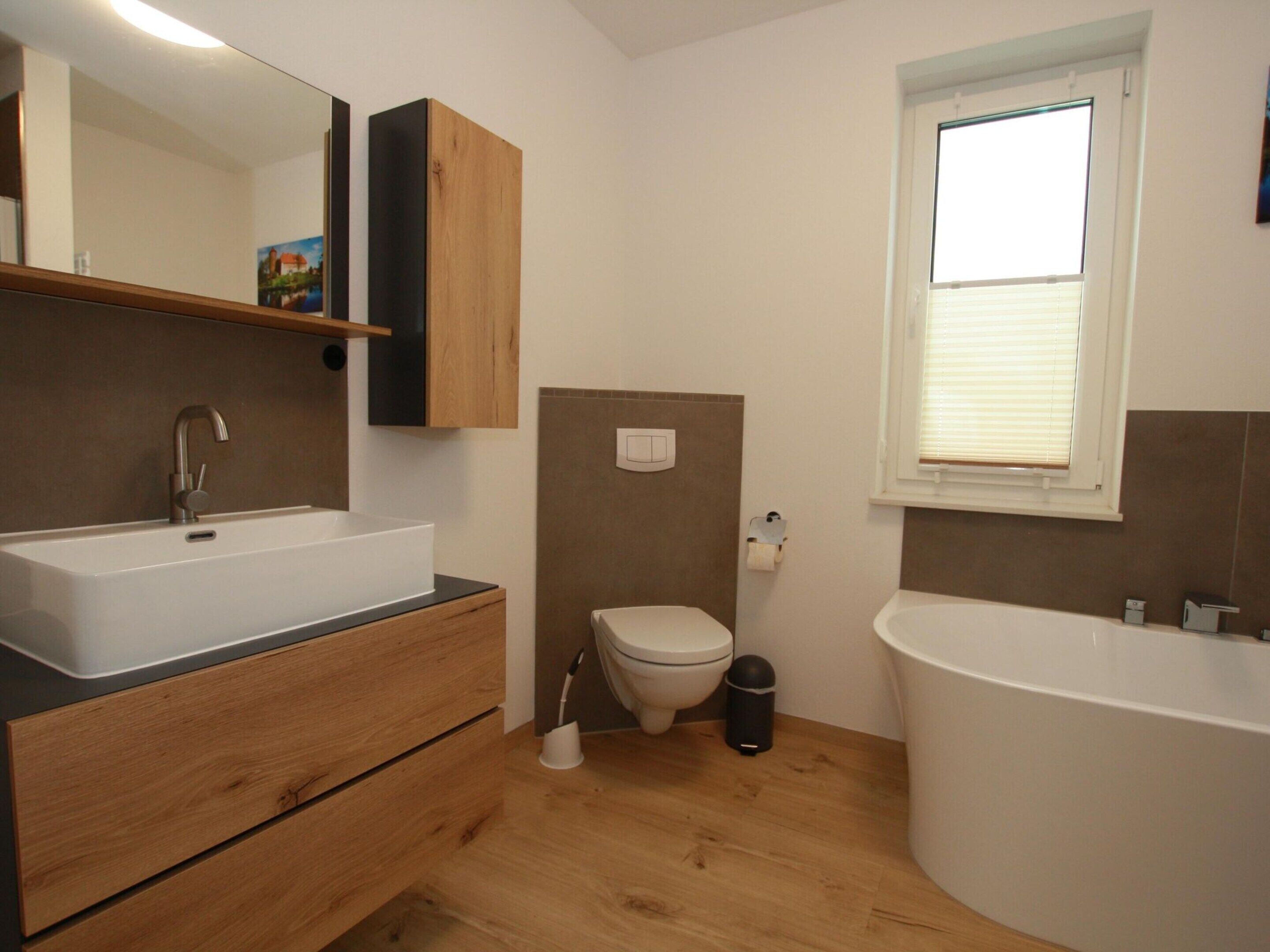 A modern bathroom with a sink, toilet, and bathtub.