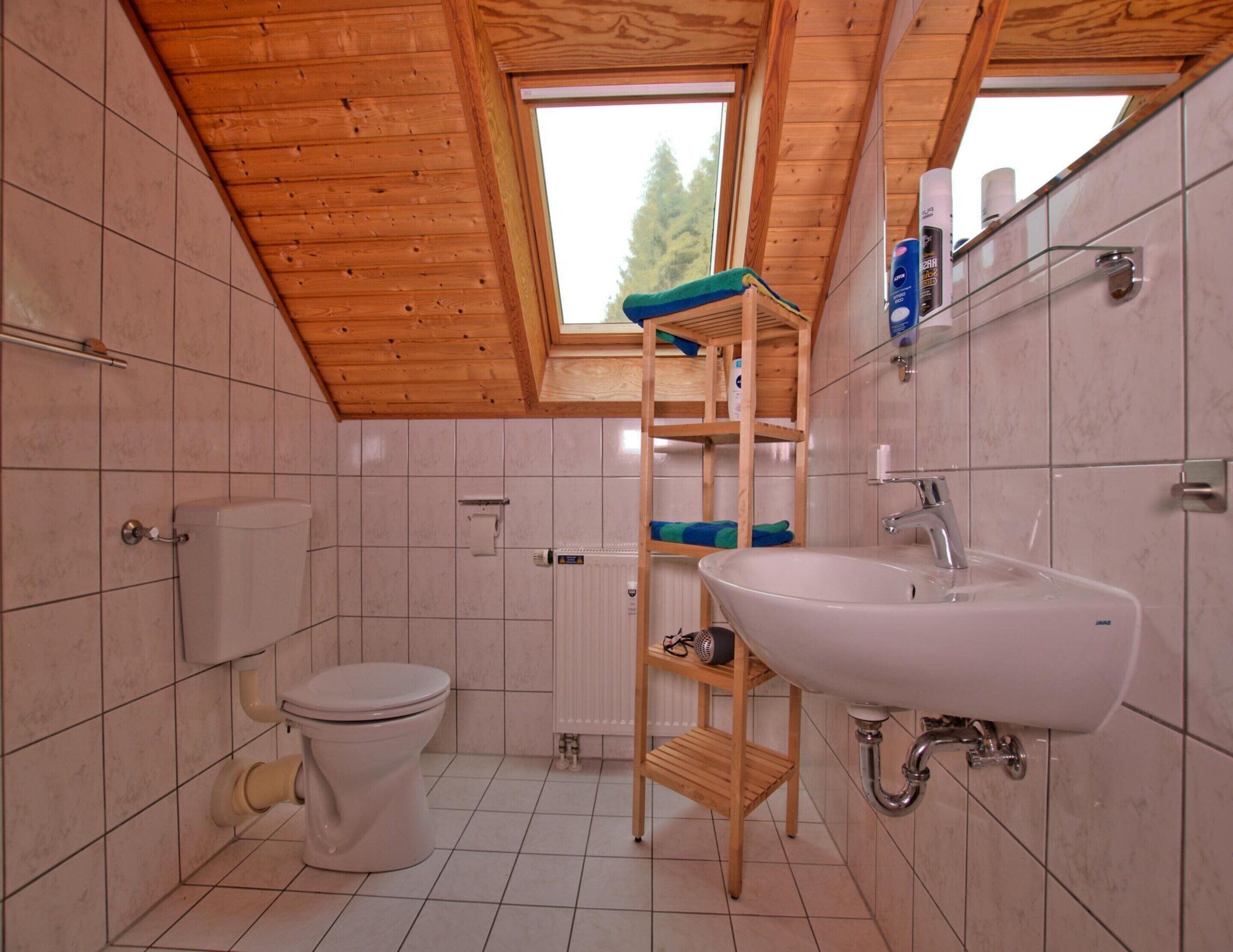 A compact bathroom with a wooden ceiling, a white sink, and a toilet.
