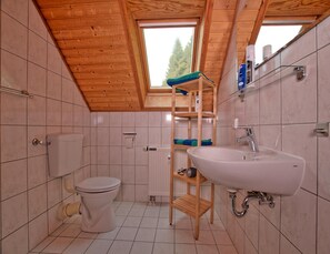 A compact bathroom with a wooden ceiling, a white sink, and a toilet. - Doppelhaushalfte in Hasselfelde (Oberharz am Brocken)