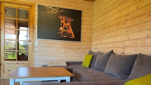 L’intérieur chaleureux d’un chalet, avec un décor en bois, un canapé, une table et un tableau encadré accroché au mur.