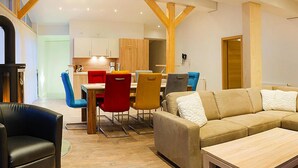 A spacious living area with a sofa, chairs, a dining table, and a kitchen in the background. - Penthouse in Niederau Near Ski Lift (Wildschönau)
