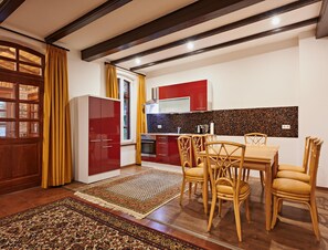 Une cuisine moderne avec des meubles de rangement rouges, une table à manger en bois avec quatre chaises et un tapis à motifs.