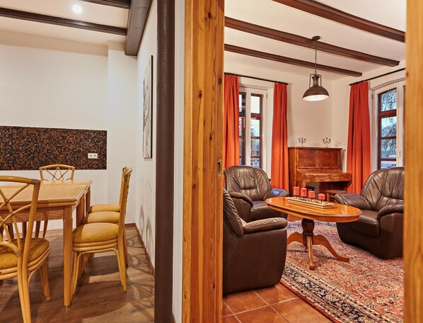 A dining area with a wooden table and chairs, a piano, and a fireplace with candles. - Ferienhaus Nahe Schlosshotel Wendorf Golf (Kuhlen-Wendorf)