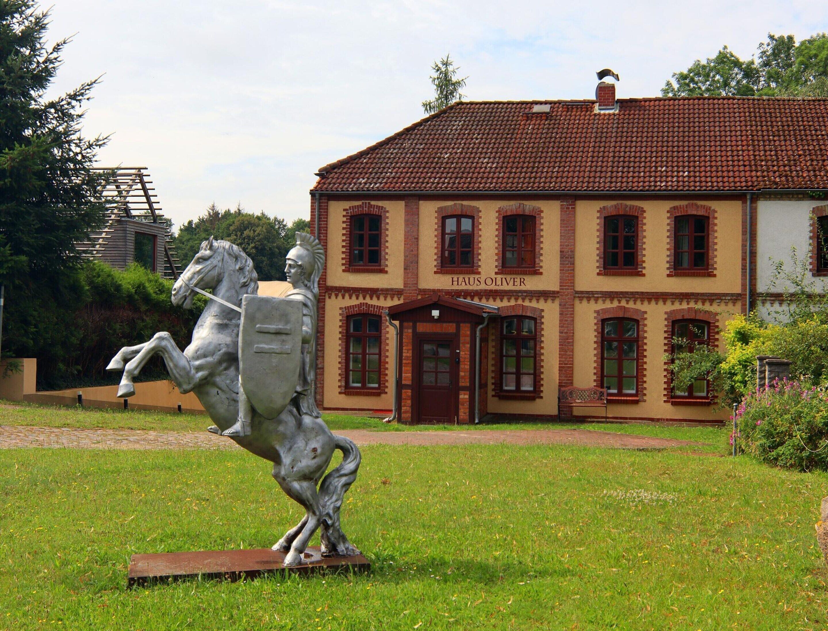 A building named "HAUS OLIVER" with a red-tiled roof and a brick facade.
