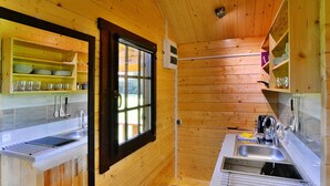 Une cuisine de taille réduite avec des murs en bois, une fenêtre et des étagères intégrées.