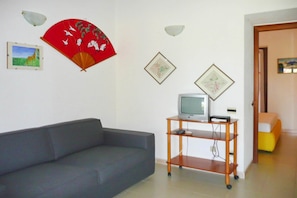 Un soggiorno con un divano grigio, una TV su un supporto in legno e luci a parete.