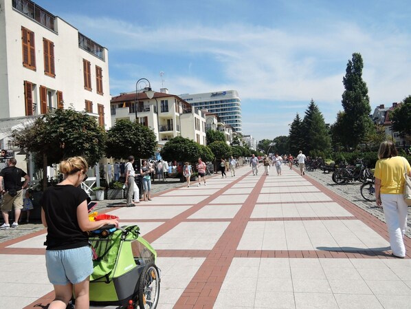 A pedestrian walkway with a green bicycle and a stroller, surrounded by buildings and trees. - Holiday Home Near Baltic Sea & Swinoujscie (Swinoujscie)