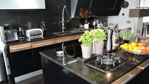 A modern kitchen with black countertops, stainless steel appliances, and a central island with a built-in stove. - Holiday Home Near Baltic Sea & Swinoujscie (Swinoujscie)