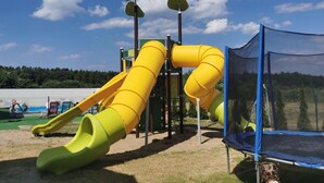 En legeplads med rutchebaner og en trampolin.