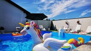 En swimmingpool med oppustelige enhjørningeflødebolde og liggestole.