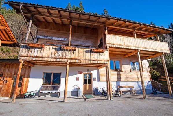 Un chalet en bois doté d’un balcon, d’un porche et d’un petit espace extérieur aménagé pour s’asseoir.