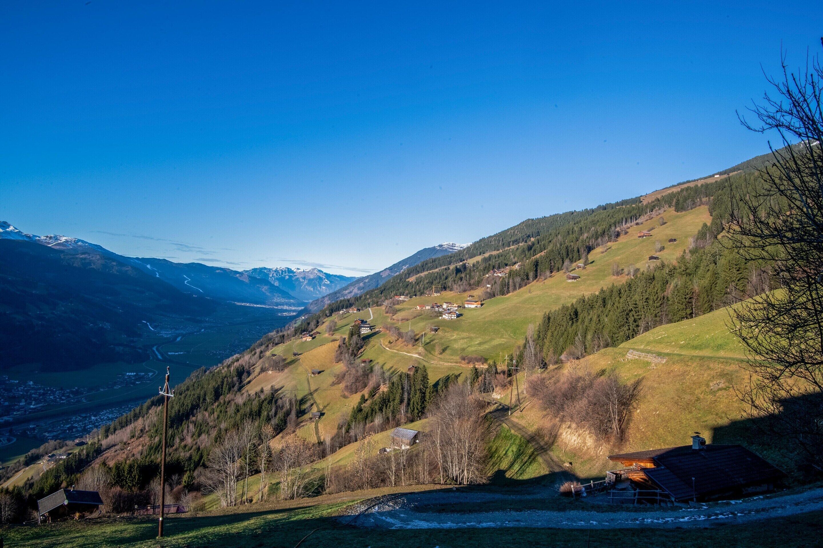 A mountainous landscape with a small village, houses, and a clear sky.