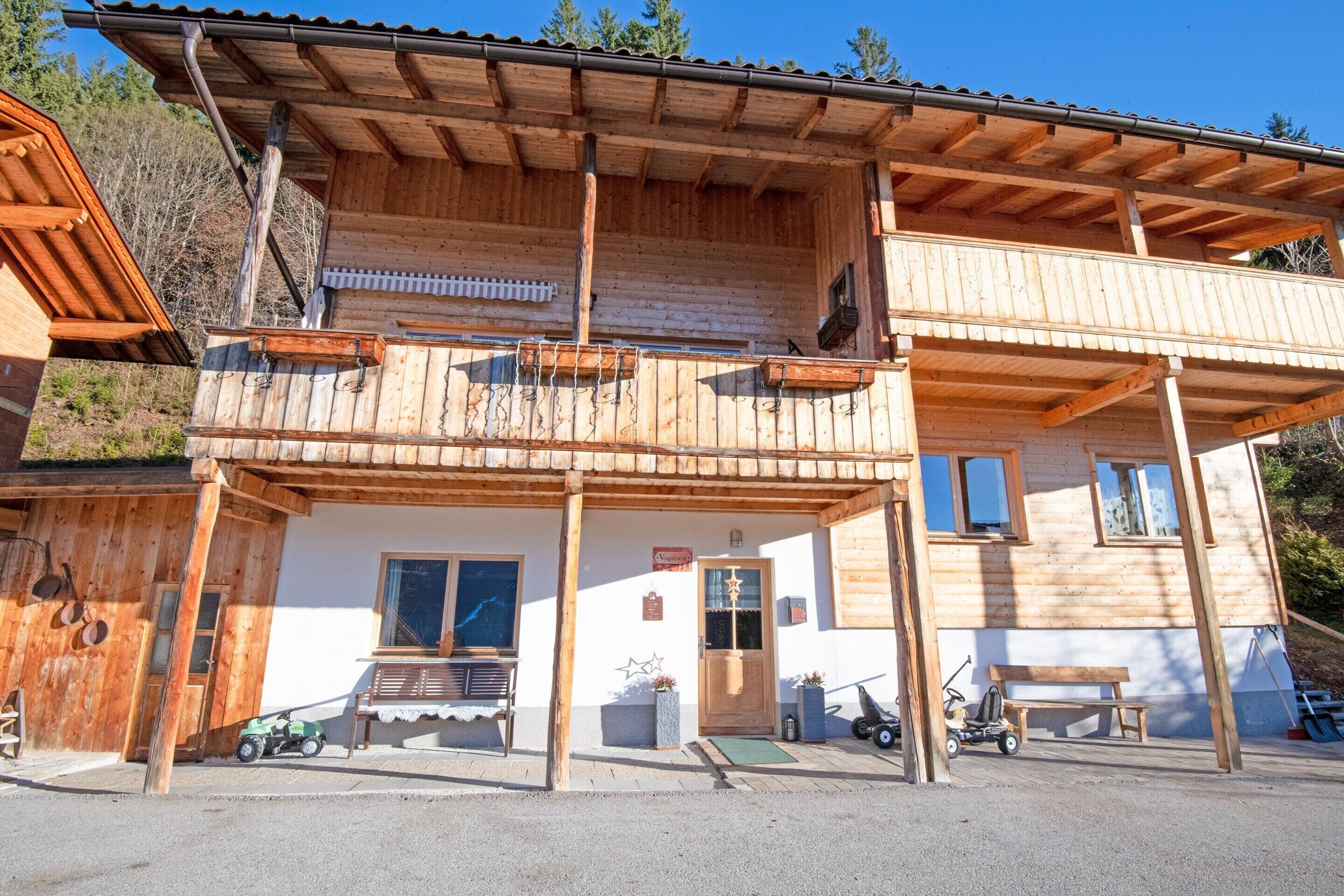 A two-story wooden building with a balcony, a bench, and a small outdoor seating area.