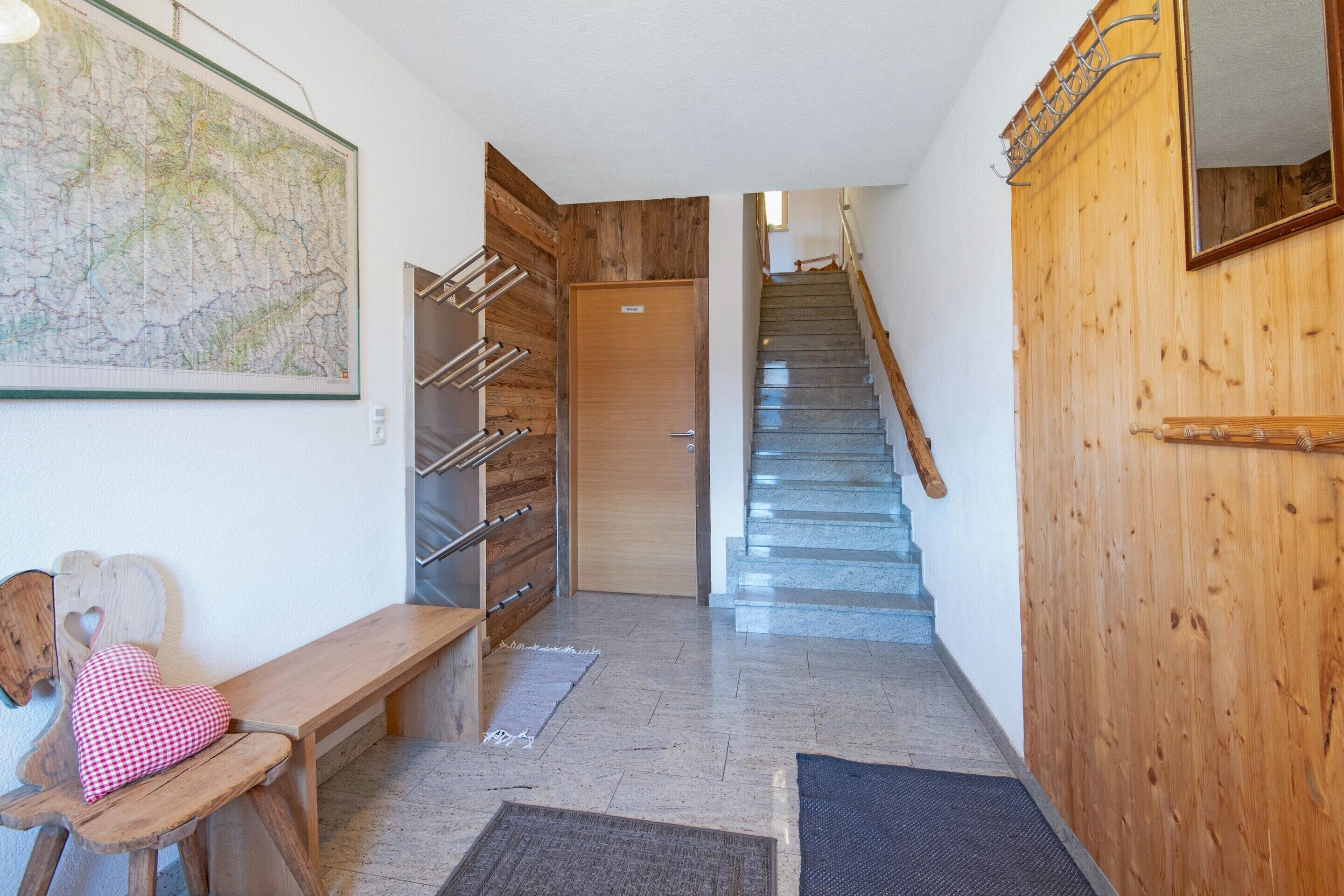 Ein Flur mit einer hölzernen Bank, einem Kleiderhaken, einer Tür und einer Treppe.