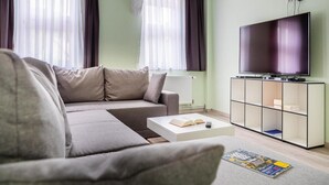 Un salon avec un canapé, une table basse, un téléviseur et une bibliothèque.