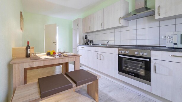 Une cuisine moderne avec des meubles en bois clair, un four encastré et un four à micro-ondes.