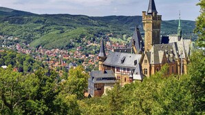 Une ville historique, avec un imposant beffroi et des bâtiments environnants, le tout se dressant sur un fond de collines verdoyantes.