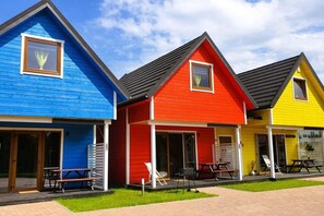 A row of colorful beach houses with sliding glass doors, each with a patio table and chairs. - Holiday Homes not far From the sea in Gaski (Mielno)