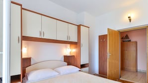 A bedroom with a bed, bedside tables, a wardrobe, and a door leading to another room. - Apartment on Vir Island Near Sandy Beaches (Vir)