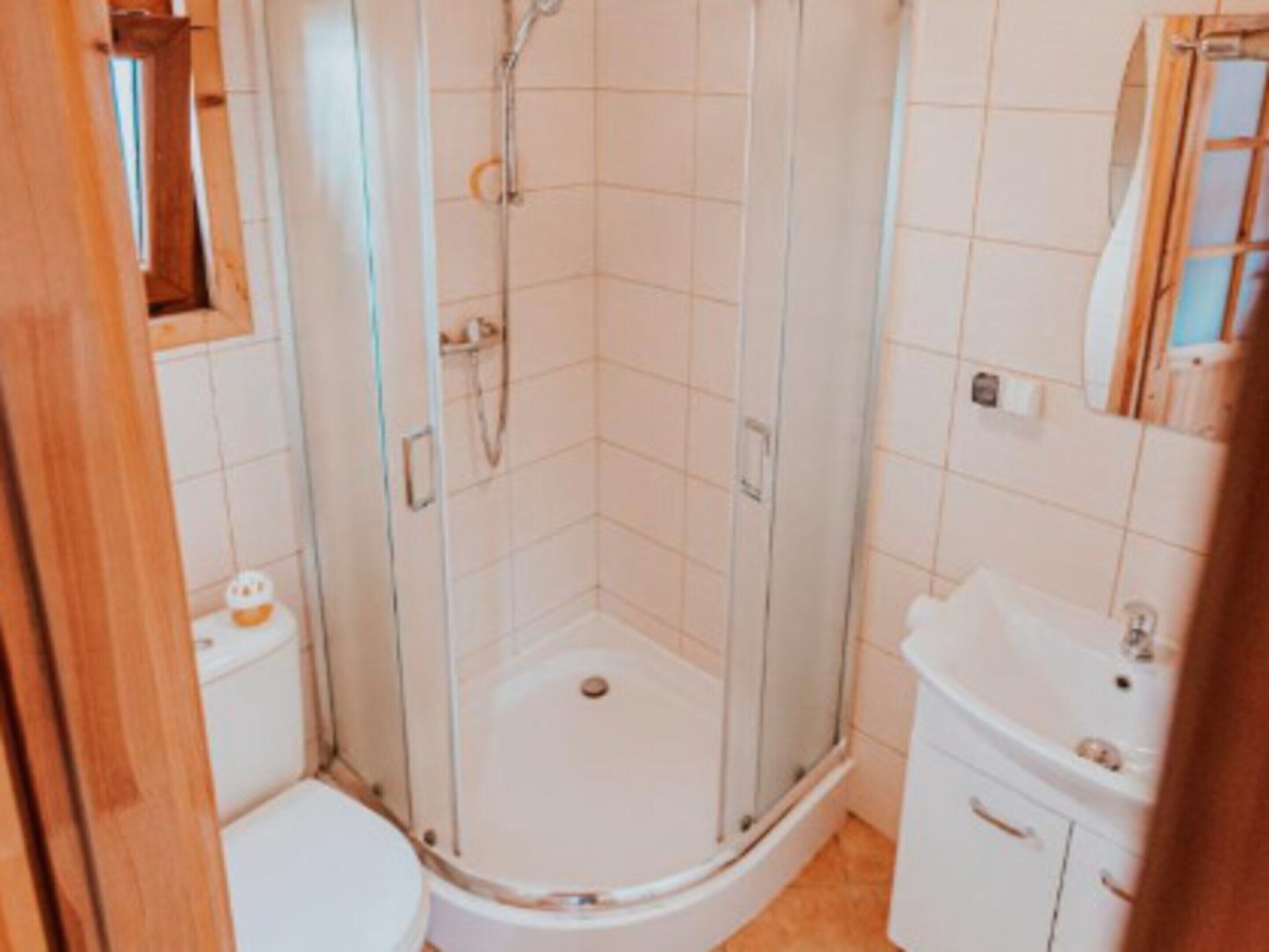 Un baño pequeño con ducha de vidrio, inodoro y lavamanos.