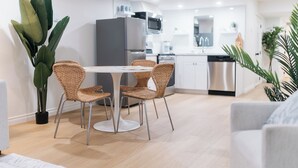 Une cuisine moderne dotée d’appareils électroménagers en acier inoxydable, un coin repas avec des chaises en osier et une plante en pot.
