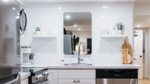 Une cuisine moderne avec des meubles blancs, des appareils en acier inoxydable et un îlot central.