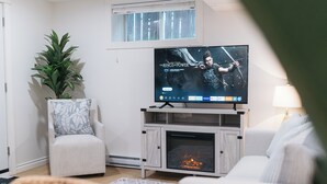 Un salon équipé d’un téléviseur à écran plat, d’une cheminée, d’une plante en pot et d’un canapé.