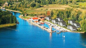 An aerial view of a marina with docked boats, a lighthouse, and residential buildings along the waterfront. - Appartement Hafenflair am Plauer See (Plau am See)