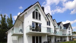 A modern two-story house with a balcony, large windows, and a well-maintained lawn. - Appartement Hafenflair am Plauer See (Plau am See)