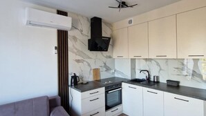 Eine moderne Küche mit weißen Schränken, einem eingebauten Backofen und einer grauen Arbeitsplatte.