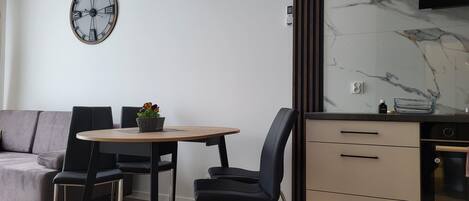 A modern kitchen with a marble backsplash, a built-in oven, and a dining area with a round table and chairs.