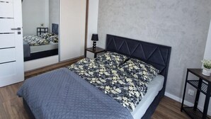 Ein modernes Schlafzimmer mit einem Bett, einem Nachttisch, einem Spiegel und einer Pendelleuchte.