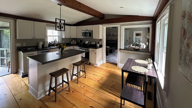 A spacious kitchen with a large island, wooden flooring, and white cabinetry. - Spacious 7 bedroom house, Near jiminy Peak  in Hancock ma , In the Berkshires (New Lebanon)