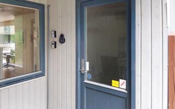 Eine Tür mit Fenster, Klingel und einem Schild mit einem roten Kreuz.