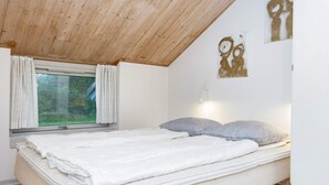 A bedroom with a bed, a window with curtains, a wall-mounted light, and a wooden ceiling. - 8 Person Holiday Home in Oksbol (Oksbol)
