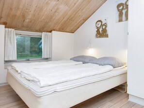 Un dormitorio con cama, ventana con cortinas, lámpara de pared y techo de madera.