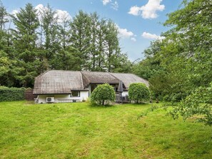 A two-story house with a tiled roof, surrounded by a grassy yard and trees. - 8 Person Holiday Home in Oksbol (Oksbol)