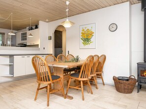 Un comedor con mesa y sillas de madera, un reloj en la pared y una chimenea.