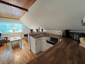 A kitchen with a wooden countertop, white cabinets, and a built-in dishwasher.