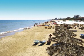 Egy strand, ahol napozóágyak és napernyők találhatók, és az égbolt felhőtlen.