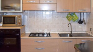 A kitchen with wooden cabinets, a microwave, an oven, a gas stove, and a sink. - Pretty Holiday Home Casa Luca With Above-ground Pool in Capezzano Pianore (Camaiore)