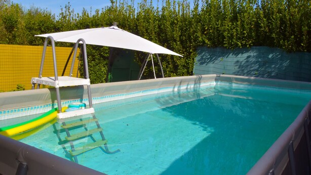 A swimming pool with a ladder, a white umbrella, and a yellow fence in the background. - Pretty Holiday Home Casa Luca With Above-ground Pool in Capezzano Pianore (Camaiore)