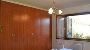 A bedroom with a large wooden wardrobe, a bed with a white headboard, and a window with curtains. - Pretty Holiday Home Casa Luca With Above-ground Pool in Capezzano Pianore (Camaiore)