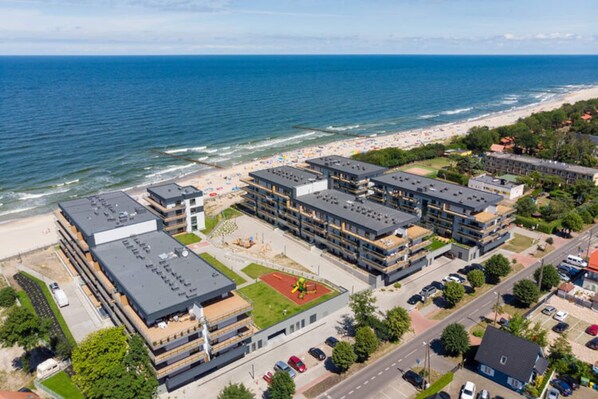 Ein Küstenhotel mit mehreren Gebäuden, einem Strand und Blick auf das Meer.