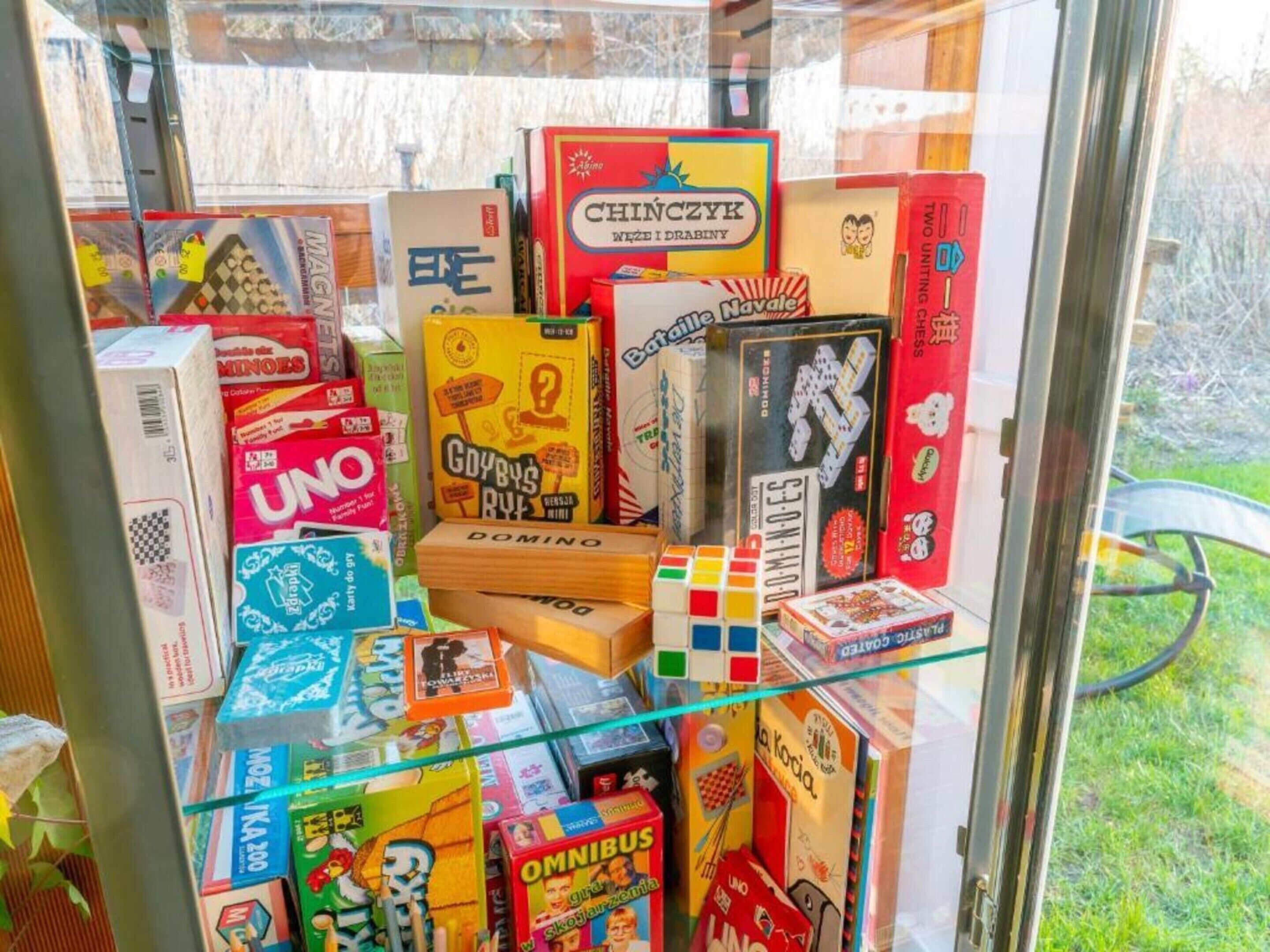 A variety of board games displayed on a glass shelf.